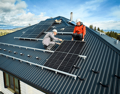 Two technicians installing solar panels on a rooftop