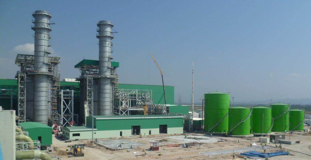 Power plant with stacks and green storage tanks