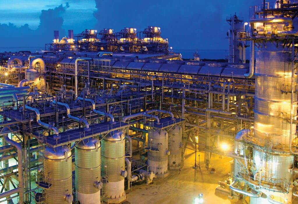 LNG processing facility with industrial pipes and tanks at night