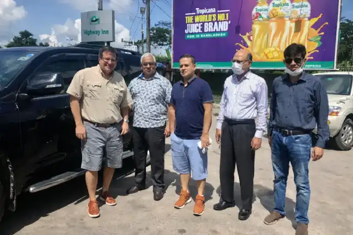 Five colleagues standing together beside vehicles