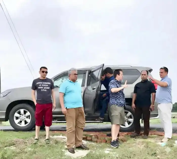 Colleagues discussing plans beside a vehicle outdoors