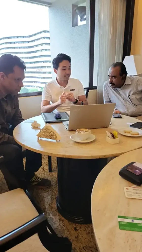 Three colleagues discussing a laptop at a table